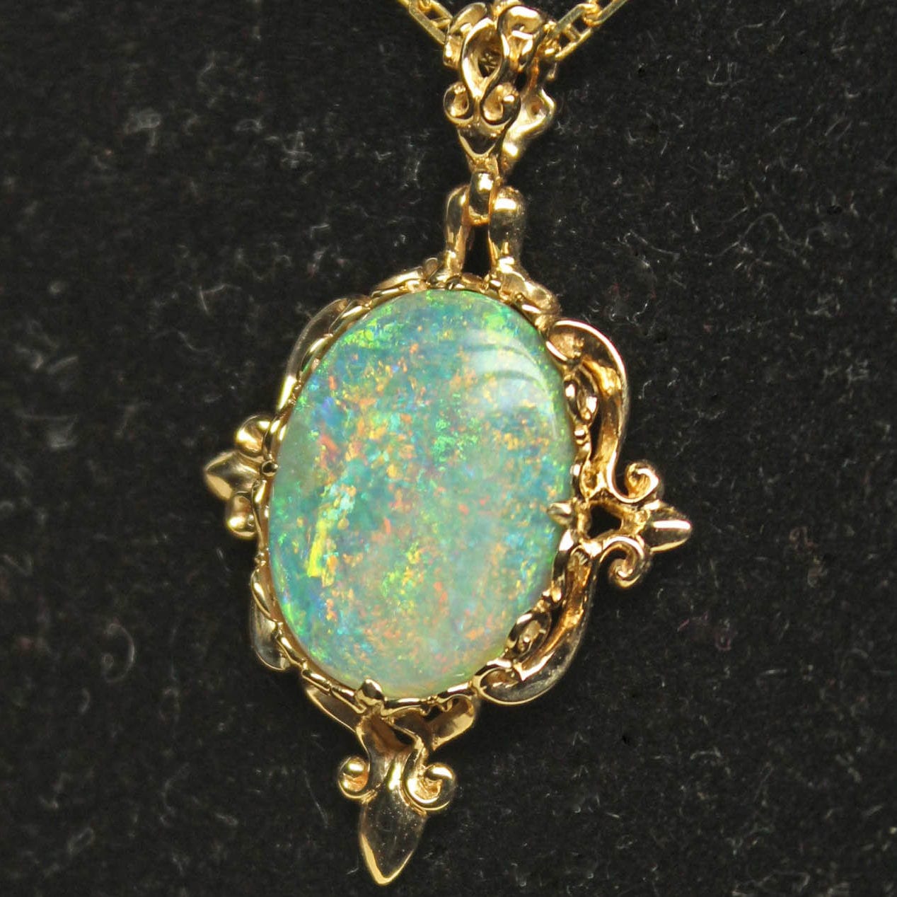 A beautiful medieval style 18K gold pendant holding a natural semi black pinfire opal from Mintabie Australia.