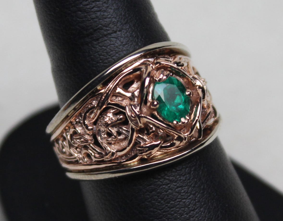 A Viking Gripping Beast wedding ring in rose 14K, and white 14K gold. The borders of the rings are high enough to protect the very fine details of the rose gold center and the fine natural emerald within. Designed and made by George Postgate.