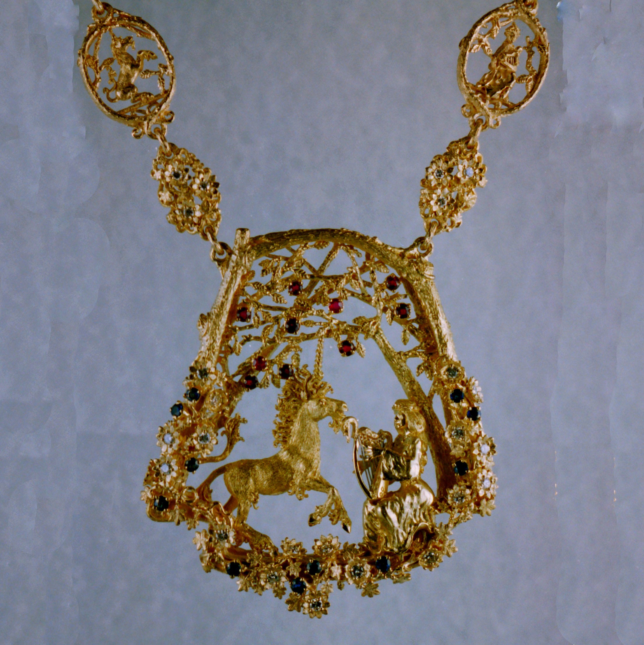 Unicorn and maiden necklace in 18K, with diamonds, sapphires and rubies by, George Postgate. A maiden playing her harp in the forest. while a Unicorn dances to her music,
